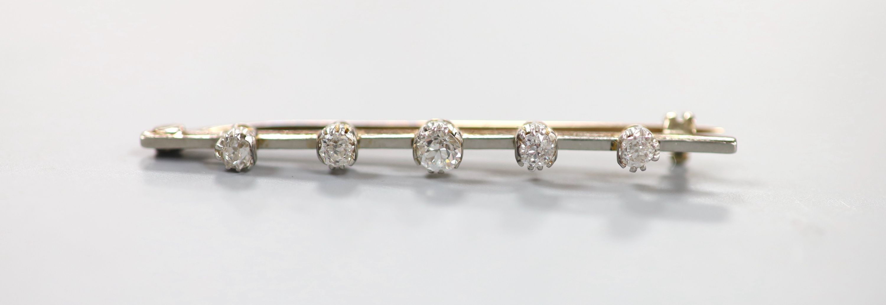 A yellow metal and graduated five stone diamond set bar brooch, 50mm, gross weight 3.7 grams.